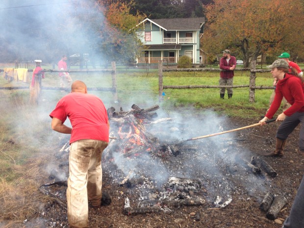 Raking burning pieces of wood along the ground to simulate a natural fire moving along the landscape.