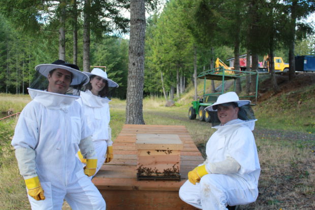 Bee Thinking's Rebekah Golden and Gabe Quitslund help CC2 Shawn Piliponis set up Larch's new beehive. Photo by Emily Passarelli.