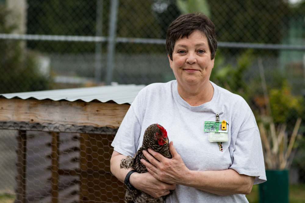 Renee Curtiss poses with a chicken at Washington Corrections Center for Women; Ms. Curtiss is one of the Roots of Success instructors at the prison. Photo by Ricky Osborne.